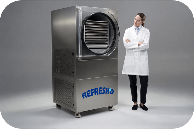 A Harvest Right commercial freeze dryer with the REFRESH'D logo on its door, a person standing beside it for scale.