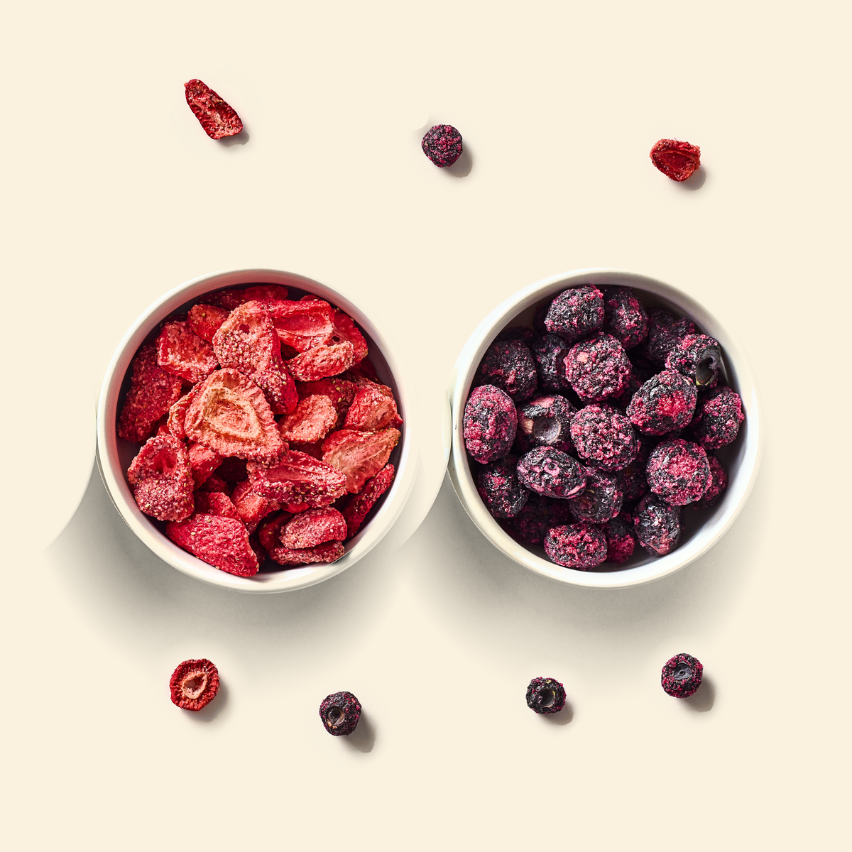 Berry Blend two-pack: a bowl of freeze-dried strawberry pieces and a bowl of freeze-dried blueberry pieces on cream, with a few loose pieces scattered around them