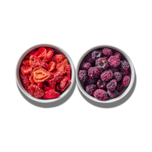 Berry Blend two-pack: a white bowl of freeze-dried strawberry pieces beside a white bowl of freeze-dried blueberries, seen from above on white