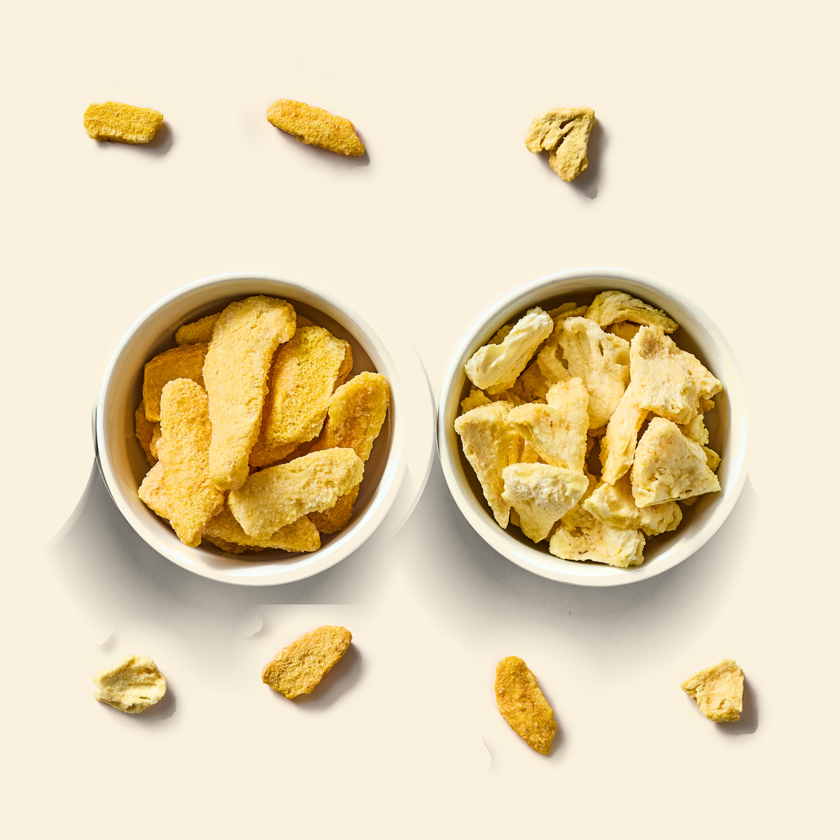 Tropical Blend two-pack: a bowl of freeze-dried mango pieces and a bowl of freeze-dried pineapple pieces on cream, with a few loose pieces scattered around them