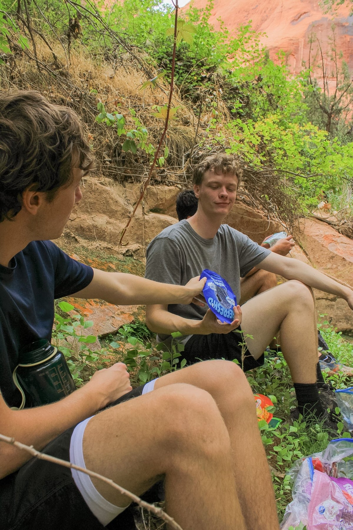 Three hikers sitting on the rock sharing a pouch
