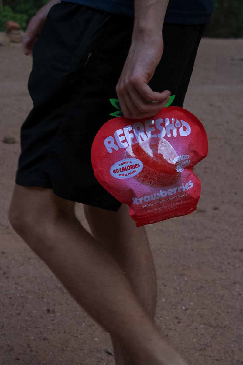 A strawberries pouch carried in one hand on a red dirt trail